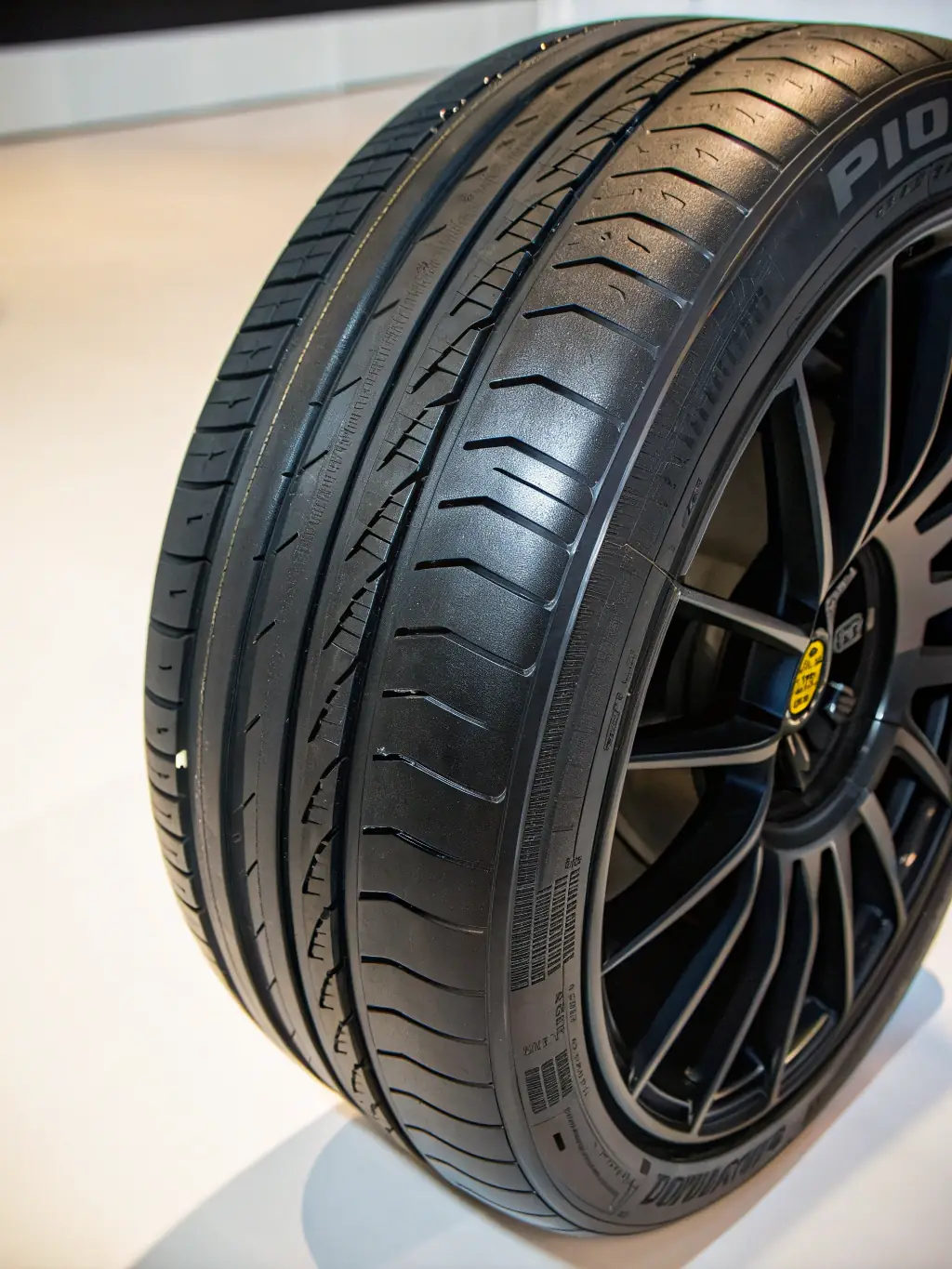 A high-angle, close-up shot of a brand new Michelin tire, showcasing its tread pattern and sidewall details, displayed in a clean, well-lit garage setting.